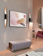 A second view of this Clérachic pair of tube wall lights beside the pink painting, with a bench and a berry-coloured chair.