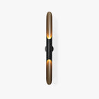 Straight on, the matt black body and gold-lined angled openings of this Clérachic wall light, on a plain white backdrop.