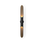 Close view of the black centre section and the gold-lined openings at each end of this Clérachic tube wall light, on white.