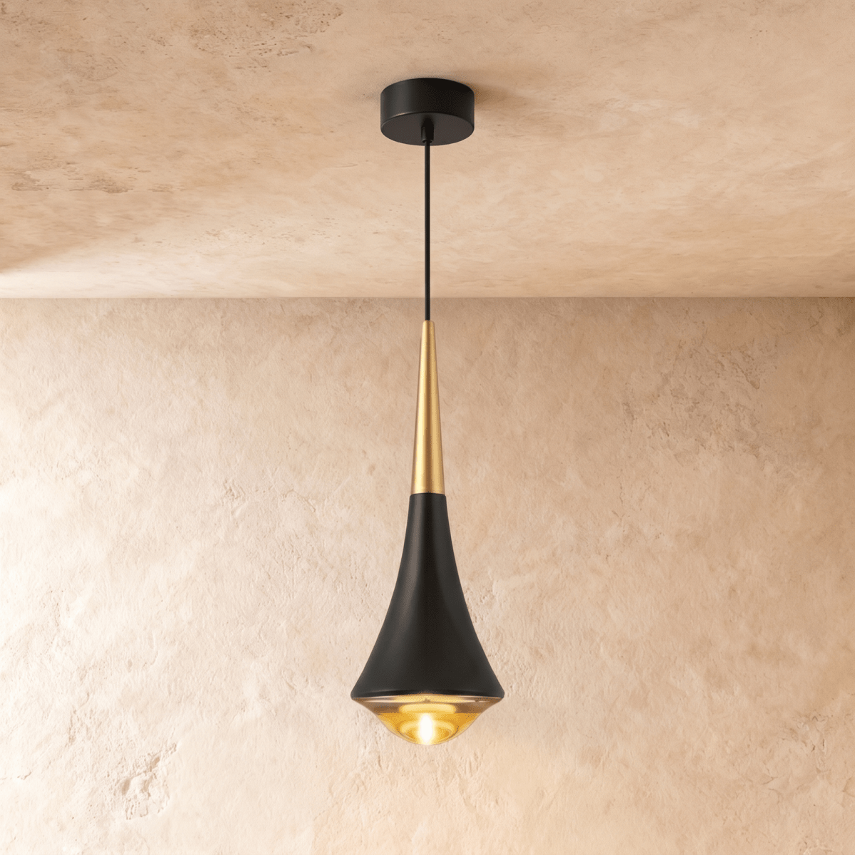Clérachic tapered pendant light in black aluminium with a gold-toned neck and a glowing glass base, on limewash.