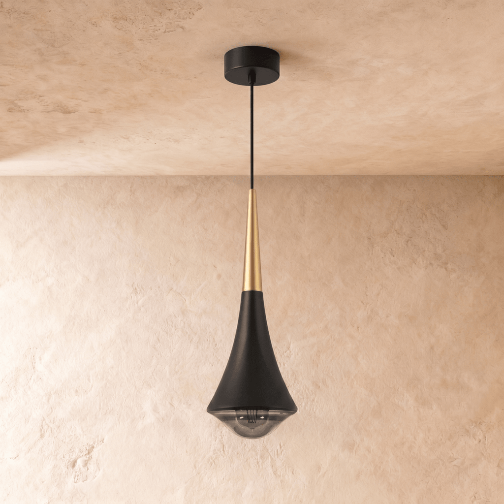 Clérachic black tapered pendant with a gold-toned neck and a smoked glass base, hanging against a limewash wall.