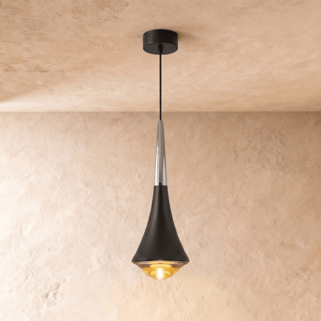 Clérachic tapered pendant light with a black body, a polished chrome neck and a warm glowing glass base, on limewash.