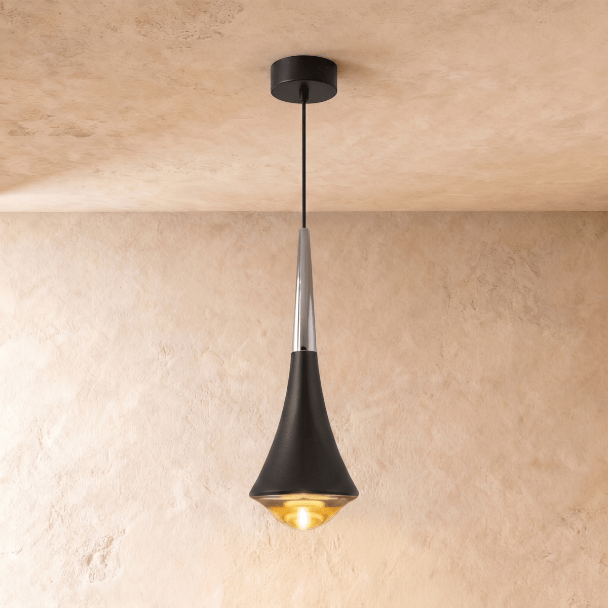 Clérachic tapered pendant light with a black body, a polished chrome neck and a warm glowing glass base, on limewash.