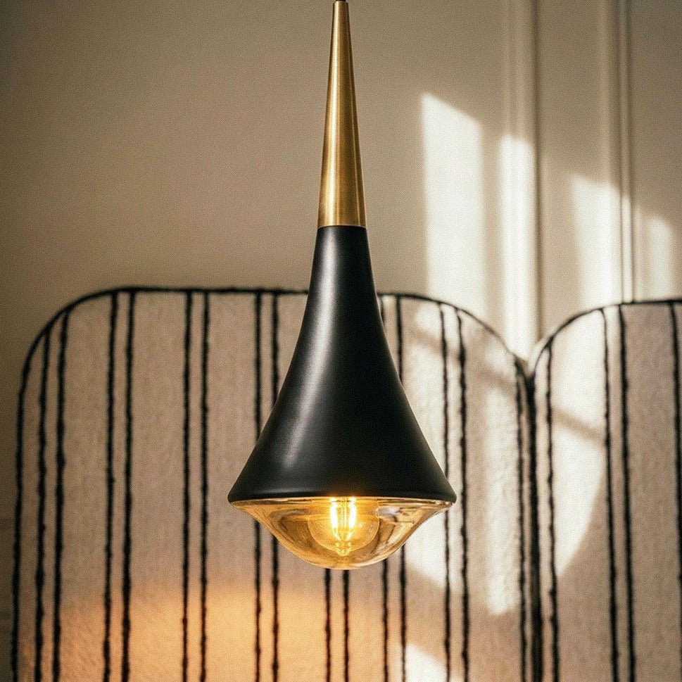 Close view of a Clérachic black tapered pendant with a gold neck, its filament-style bulb lit in the glass base.
