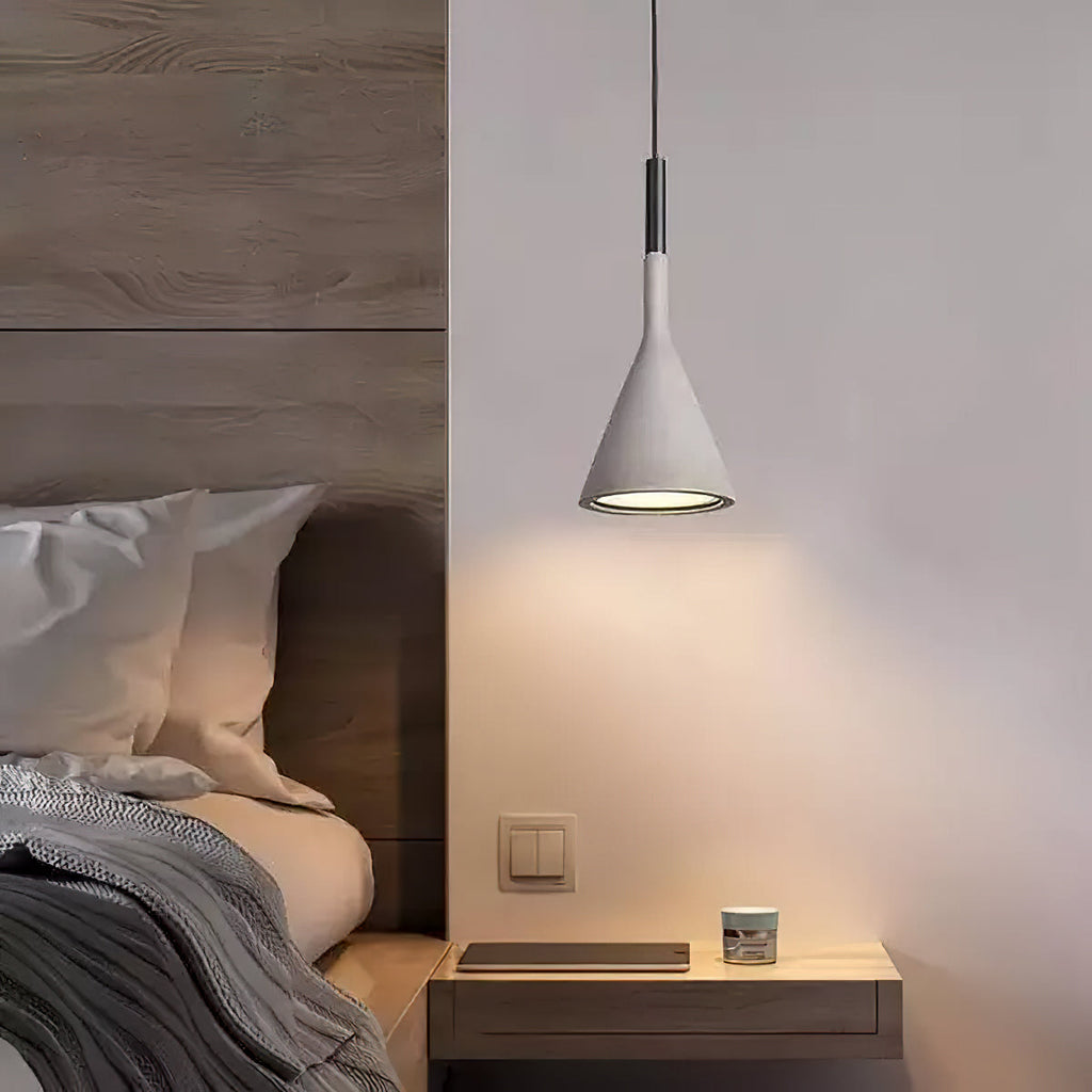 Lit grey Clérachic pendant beside a wooden headboard and a floating bedside shelf, casting a warm pool of light below.