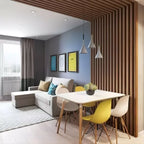 Three small grey Clérachic pendants over a white dining table with yellow chairs, in front of a slatted wood divider.