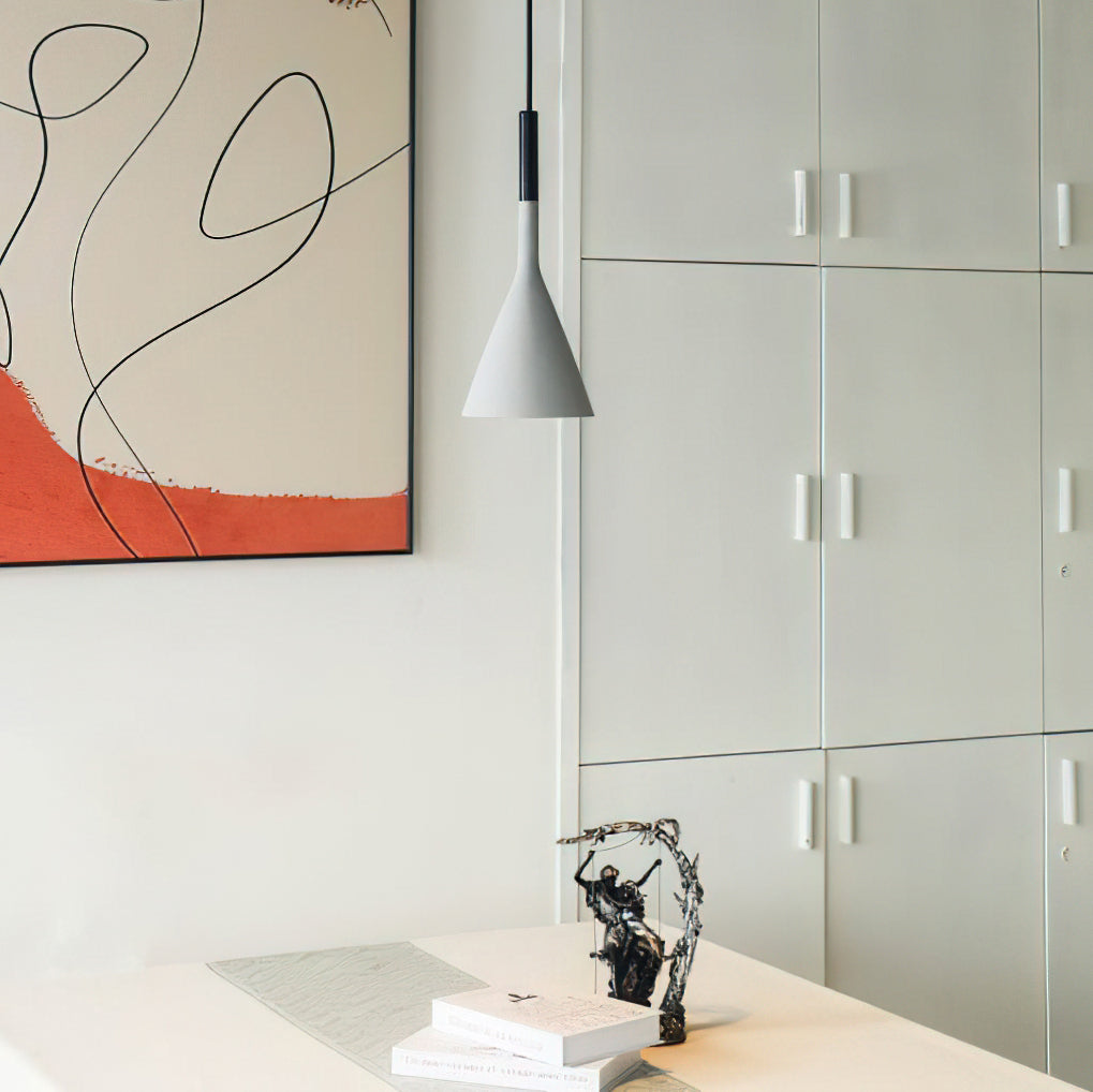 Light grey concrete Clérachic pendant beside an abstract print and white cabinet doors, above a white table with books.