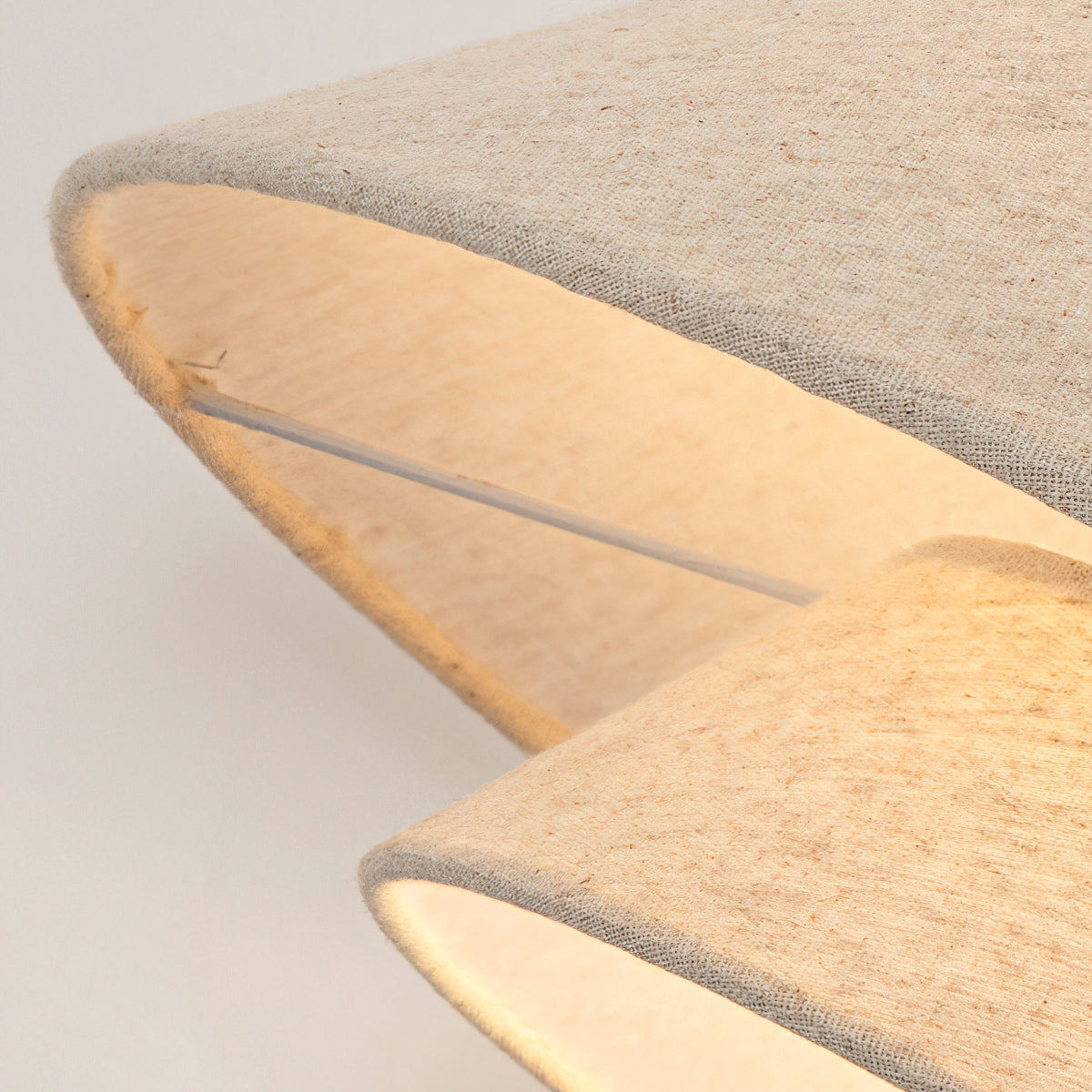 Close view of the stitched linen edge of the upper shade and the lower tier of this Clérachic pendant, lit from within.