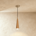 Clérachic tapered wooden cone pendant in a light natural finish with a silver-tone canopy and a bare globe bulb, on limewash plaster.