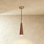 Clérachic tapered cone pendant in a deep reddish walnut finish with a silver-tone canopy and black cord against limewash plaster.