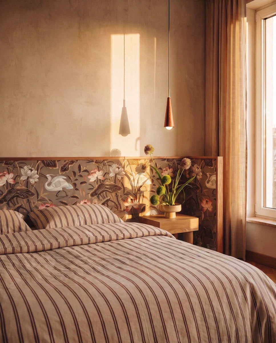 Clérachic two small wooden cone pendants hung by a striped bed with floral panelling, soft evening light across the wall.