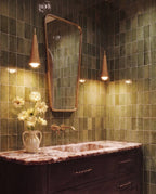 Clérachic two warm-glowing wooden cone pendants hung against green glazed tiles beside a mirror and a marble-top vanity.