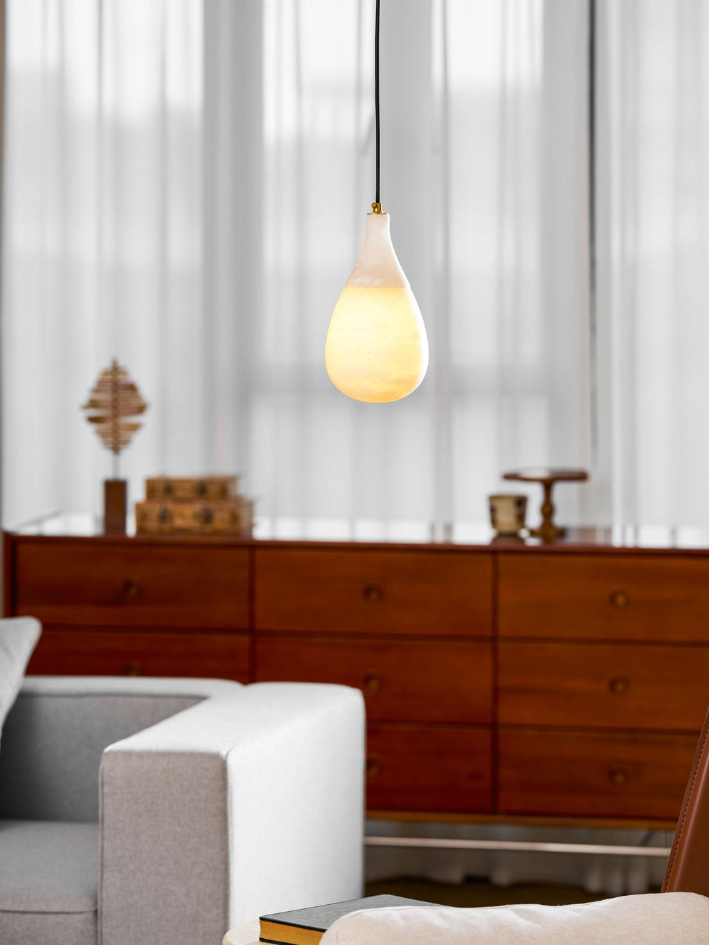 With the light on, the lower half of this Clérachic alabaster drop glows warm in front of sheer curtains.