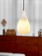 Close view of this Clérachic alabaster pendant lit, its lower half glowing amber while the neck stays pale.