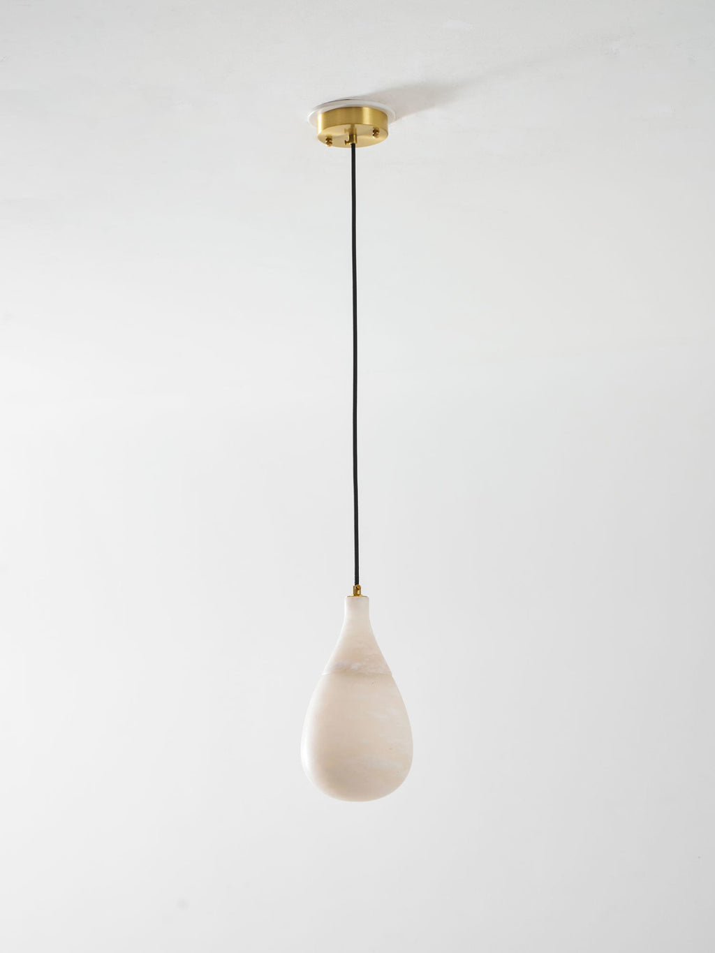 Small unlit Clérachic alabaster drop hanging from a brass ceiling plate on a thin black cord, on a pale backdrop.