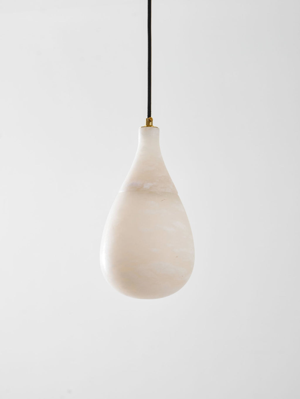 The unlit milky-white shade of this Clérachic pendant, with soft veining and a brass collar at the top.