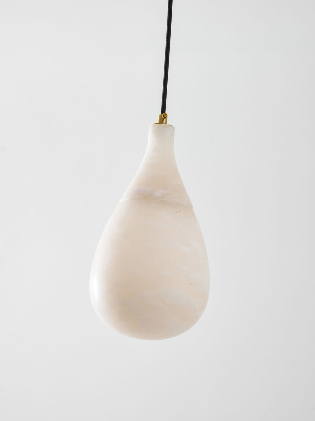 A larger, unlit Clérachic alabaster drop with pale cloudy veining, hung from a black cord with a brass collar.