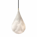 A Clérachic alabaster teardrop with swirling grey and white veining and a brass-tipped black cord, on white.