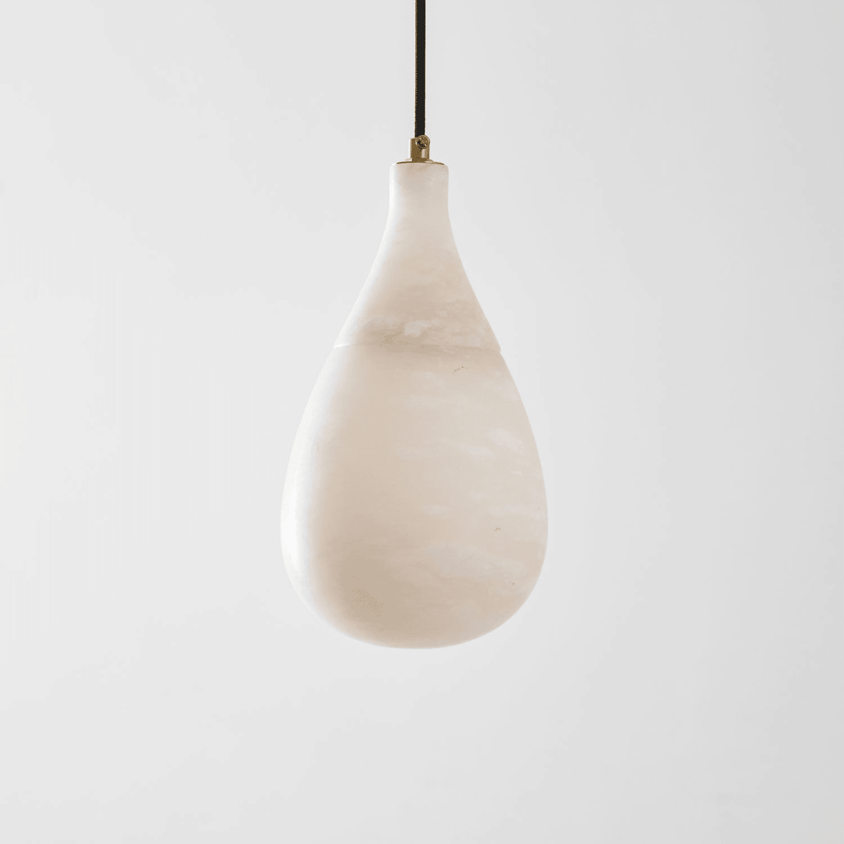 Unlit Clérachic alabaster drop with soft cloudy veining, hanging on a dark cord against a light grey backdrop.