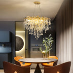 Clérachic teardrop chandelier lit over a round dining table in a dark kitchen with a lit disc.