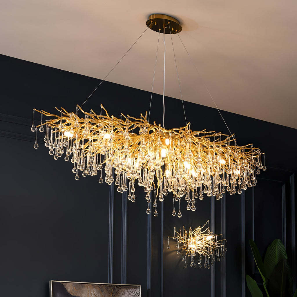 The long Clérachic teardrop chandelier lit on a navy wall, a smaller matching piece beyond.