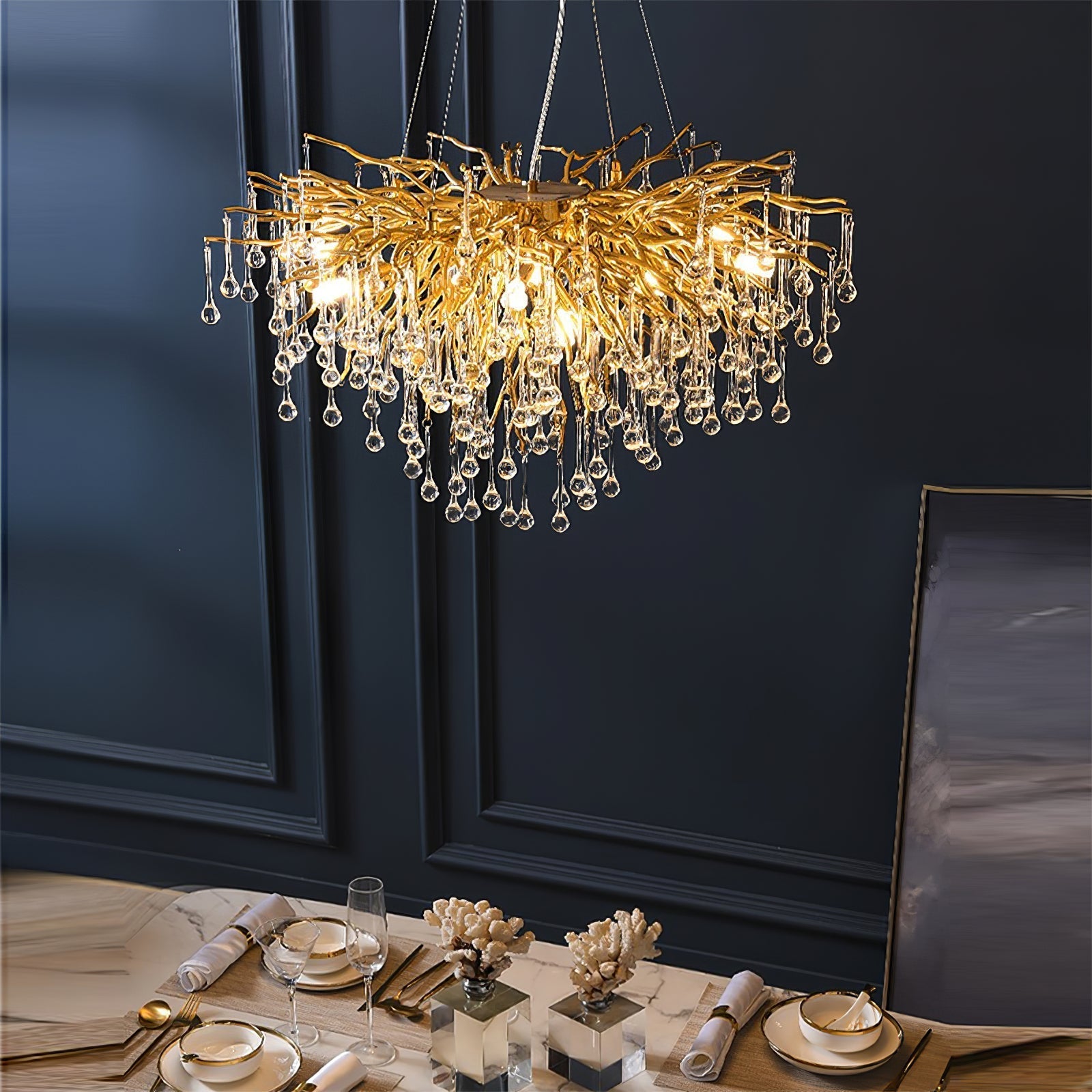 The Clérachic teardrop chandelier lit above a laid table beside a framed artwork.