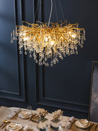 Clérachic teardrop chandelier lit low over a marble table set with coral and glassware.
