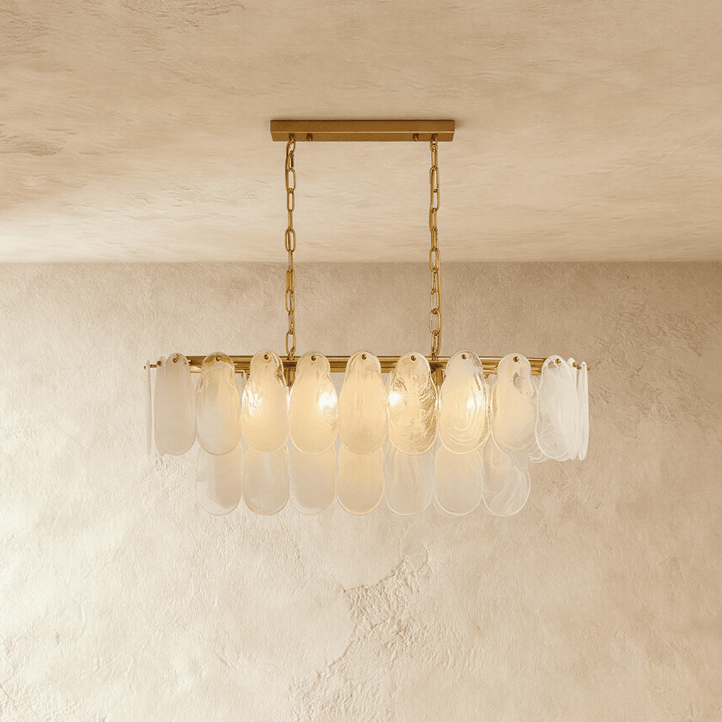 Clérachic linear chandelier with overlapping frosted glass teardrop shades on a brass bar, hung from two chains.