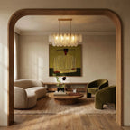 Clérachic linear glass chandelier lit warm above a low table, framed by an oak arch in a calm living room.