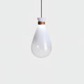 Single white Clérachic teardrop pendant with a leather strap at the neck, glowing softly against a pale grey backdrop.
