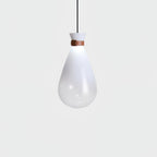 Single white Clérachic teardrop pendant with a leather strap at the neck, glowing softly against a pale grey backdrop.