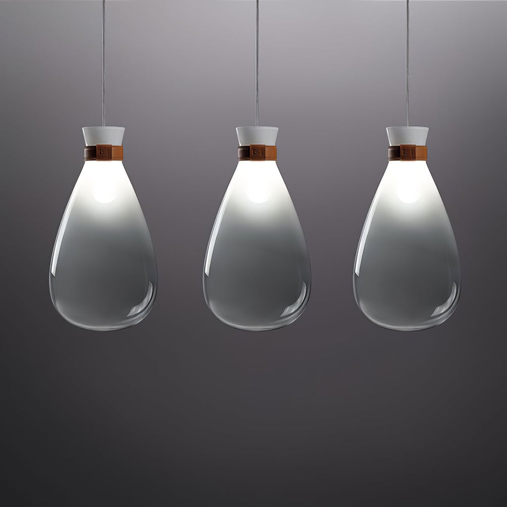 Three grey-gradient Clérachic teardrop pendants in a row, lit at the neck, against a dark grey backdrop.