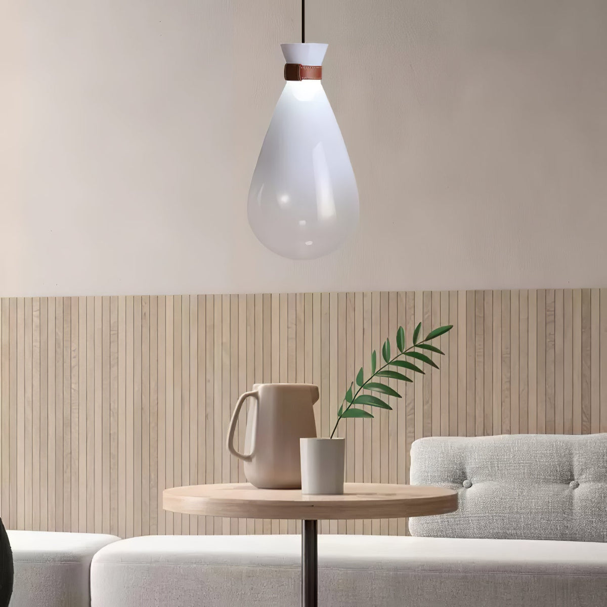 White Clérachic teardrop pendant above a small round wooden table, with a jug and a leafy stem against a slatted wall.