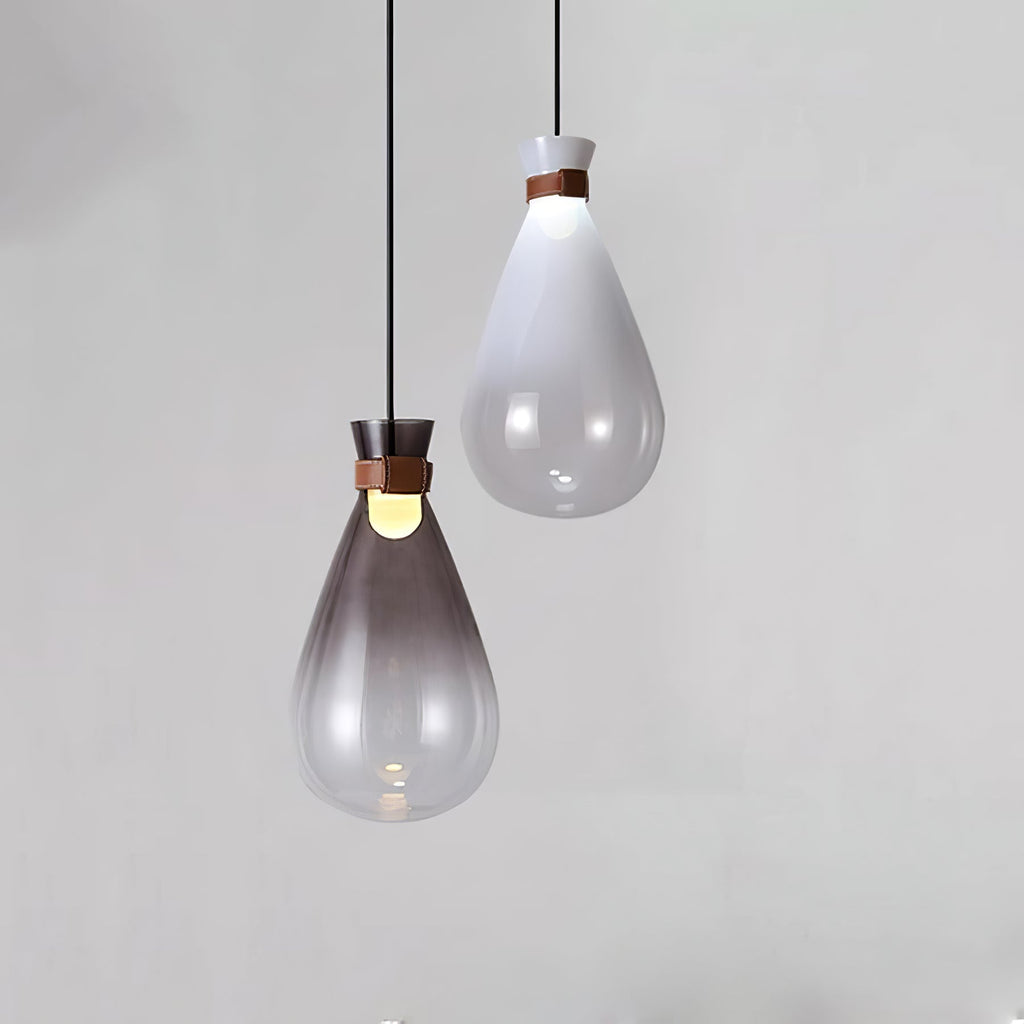 A smoke-grey and a white Clérachic teardrop pendant at different heights against a light grey wall, each lit at the neck.