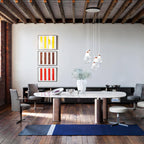 Cluster of Clérachic teardrop pendants over a long oval table in a loft with exposed beams, with striped prints behind.