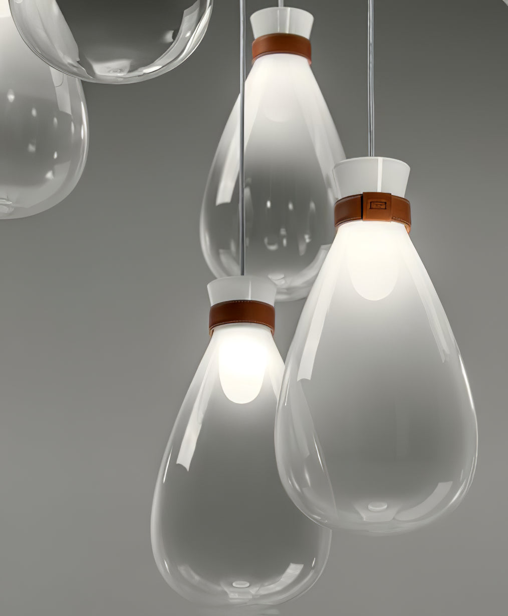 Close view of frosted-white Clérachic teardrop pendants with tan leather straps, lit at the neck against a grey backdrop.