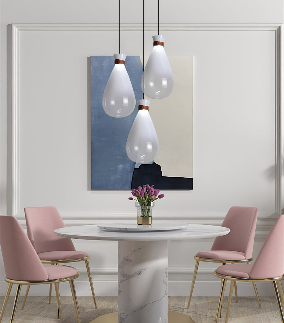 Three white Clérachic teardrop pendants above a round marble pedestal table with pink chairs and a blue abstract painting behind.