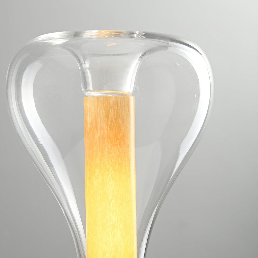 Close view of the clear glass shoulder and lit amber column inside this Clérachic lamp, against a pale grey backdrop.