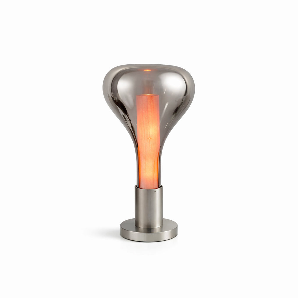 On white, a smoke-grey teardrop lamp with an orange glowing core stands on a round chrome base, from Clérachic.
