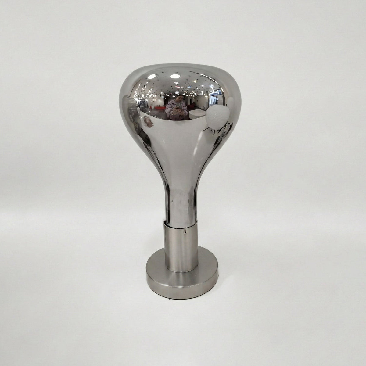 A pale grey backdrop behind this Clérachic lamp: a polished mirror-finish shade over a brushed round base, switched off.
