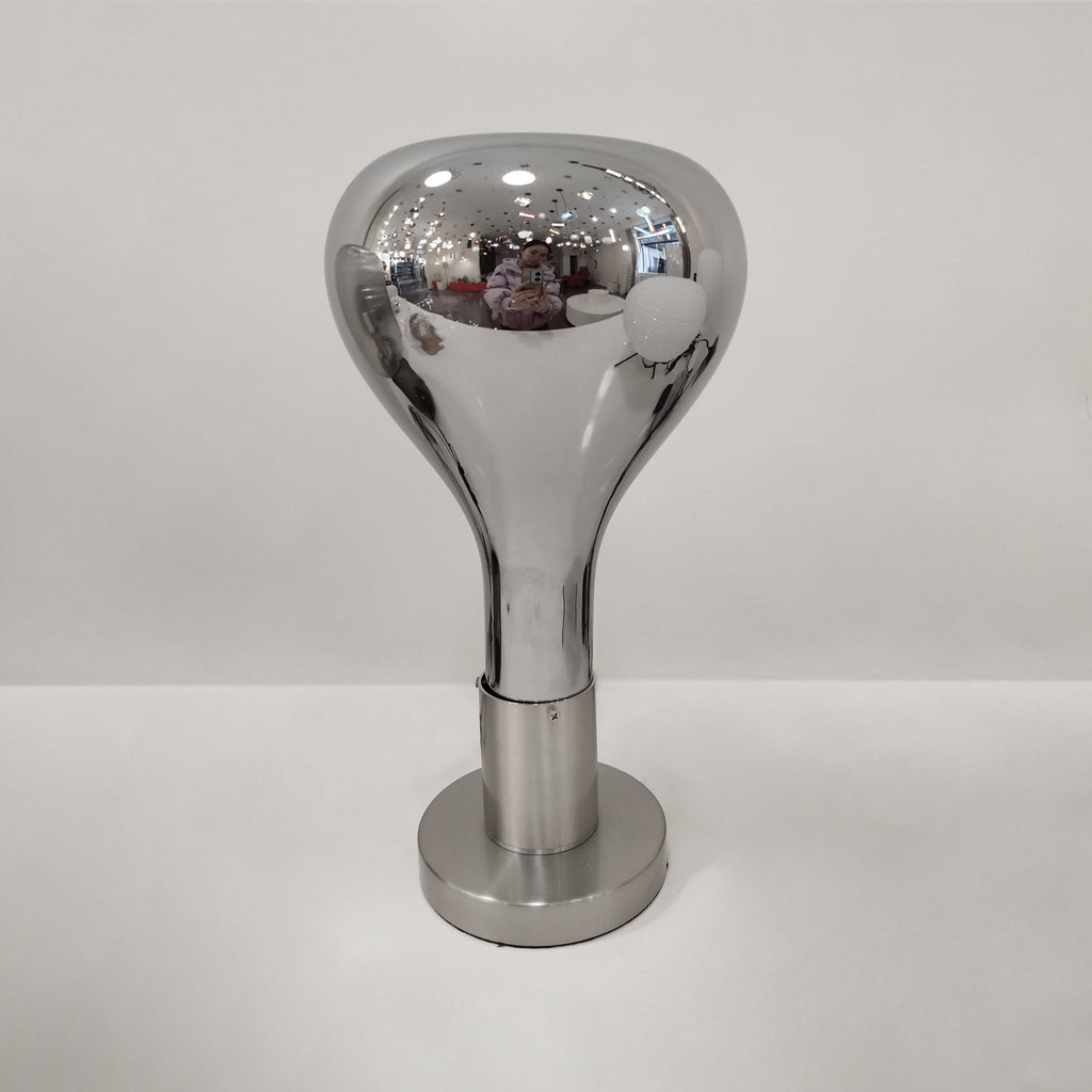 Tight view of a mirror-chrome teardrop shade and brushed stem, on a pale grey backdrop, from Clérachic.