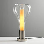Slightly tinted clear glass surrounds a lit pale-amber core on this Clérachic lamp, on a round brushed-metal base.