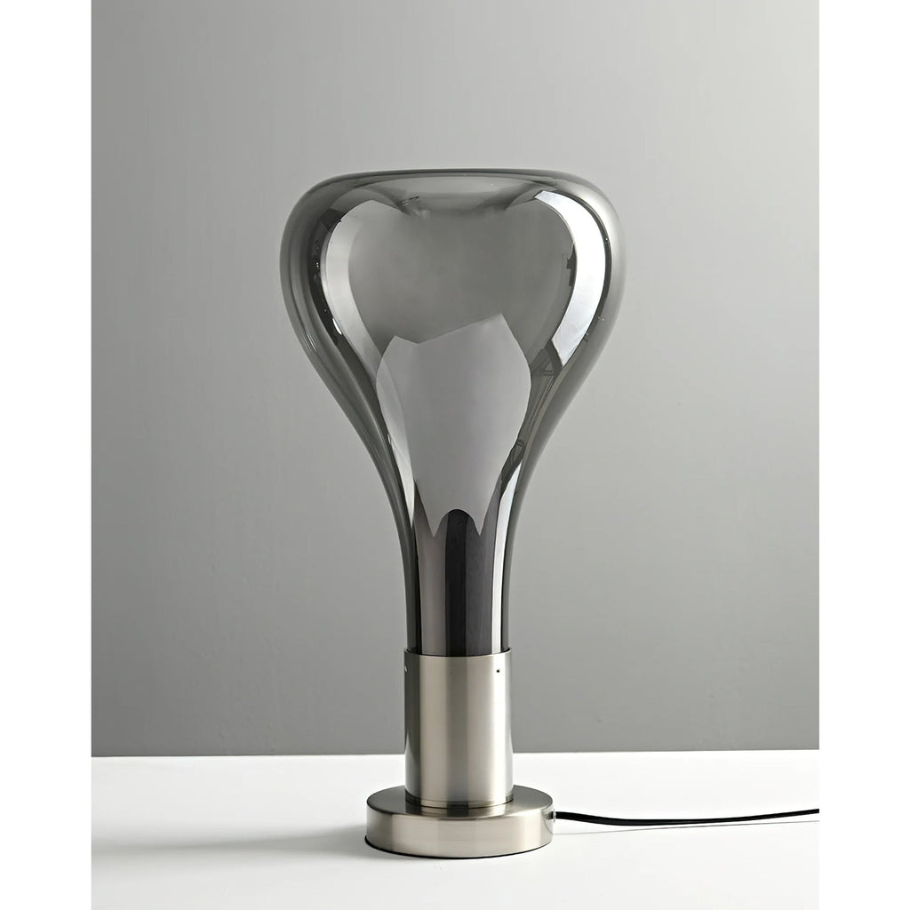 An unlit smoke-grey glass teardrop lamp on a brushed metal stem and base, with a black cord, against a soft grey wall, from Clérachic.