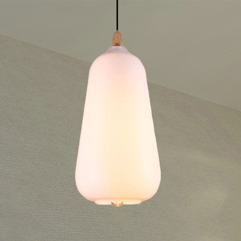 Clérachic teardrop glass pendant light in white opal, lit to a soft cream glow against a pale sage wall.