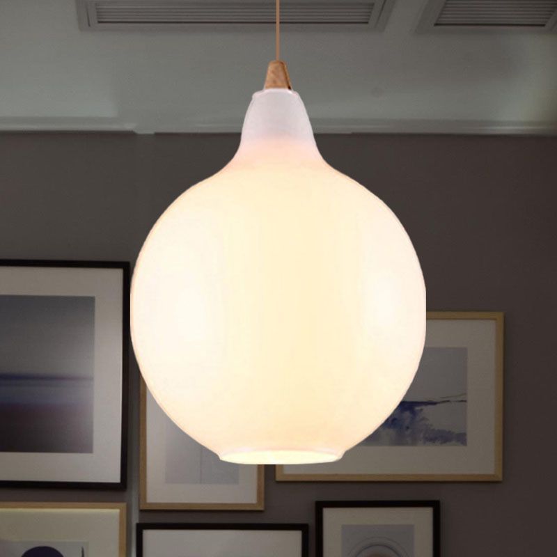 Clérachic globe pendant in white opal glass, a full round shade lit softly above a gallery wall of frames.