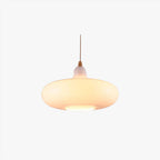 Studio shot of the Clérachic saucer pendant in white opal glass, lit on its slim cord against a plain backdrop.
