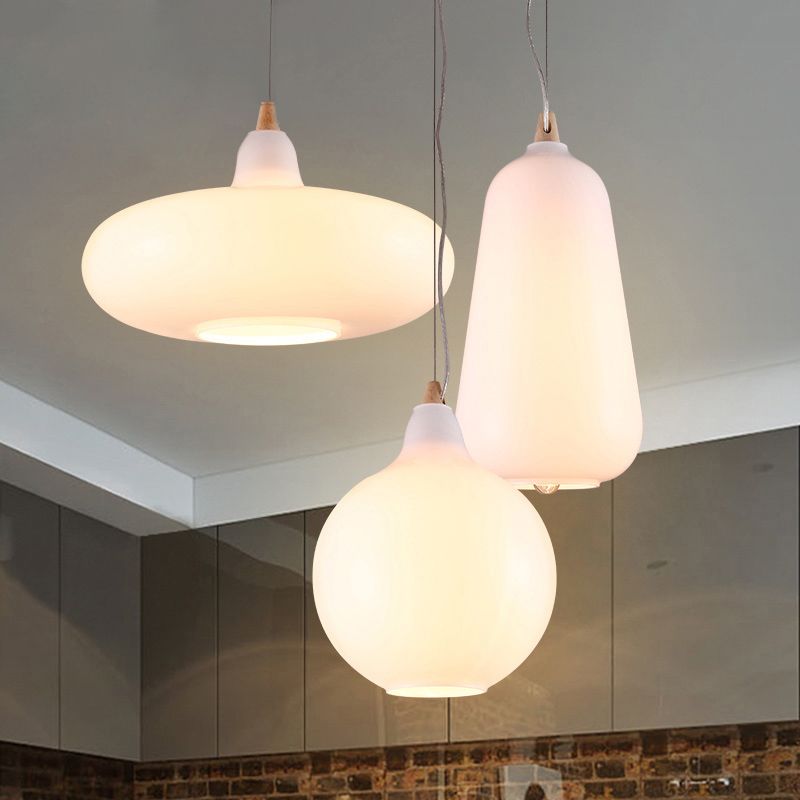 Clérachic glass pendants grouped over a kitchen — the white saucer, teardrop and globe shades at staggered heights.