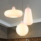 Clérachic glass pendants grouped over a kitchen — the white saucer, teardrop and globe shades at staggered heights.
