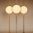 Clérachic floor-to-ceiling lamps shown together in brass, silver and vintage brass, each lit and standing on its small round floor foot.