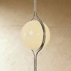 Clérachic floor-to-ceiling lamp in silver, an oblique view against pale plaster, the ring reading as a band across the lit globe.